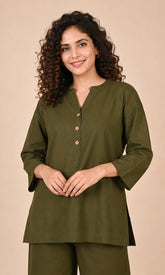 A woman with curly brown hair wearing an olive green long-sleeve Co-ord set with a buttoned split neckline, paired with matching olive green trousers, set against a solid beige background.