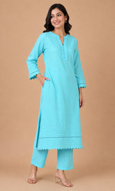 A woman modeling a light blue kurta and matching trouser set against a solid beige studio background.