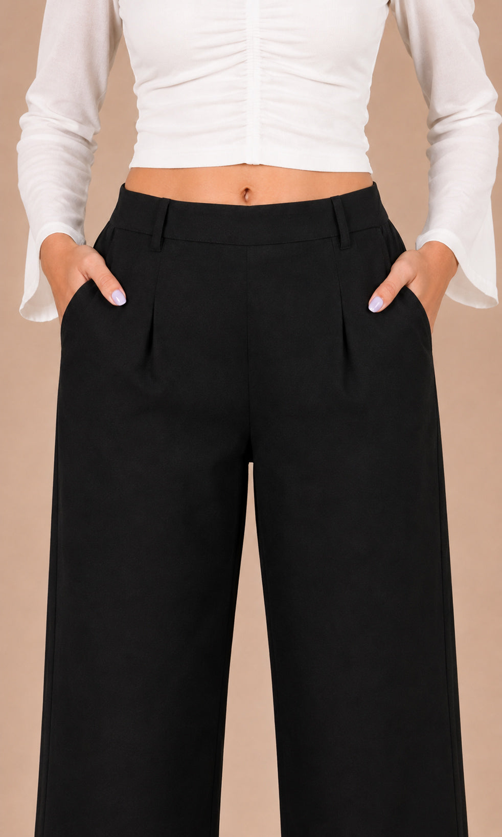 A model wearing black wide-leg trousers with pleats and side pockets, paired with a white long-sleeve crop top, against a solid beige background.