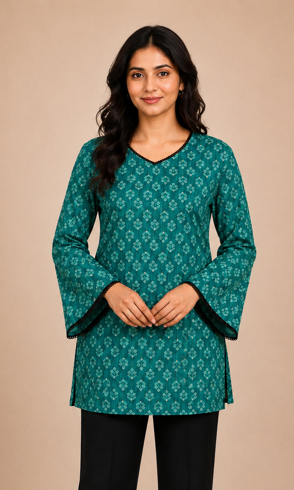 A woman modeling a teal green kurti with a white geometric pattern, black trim at the neckline and cuffs, and black pants, set against a solid beige studio background.