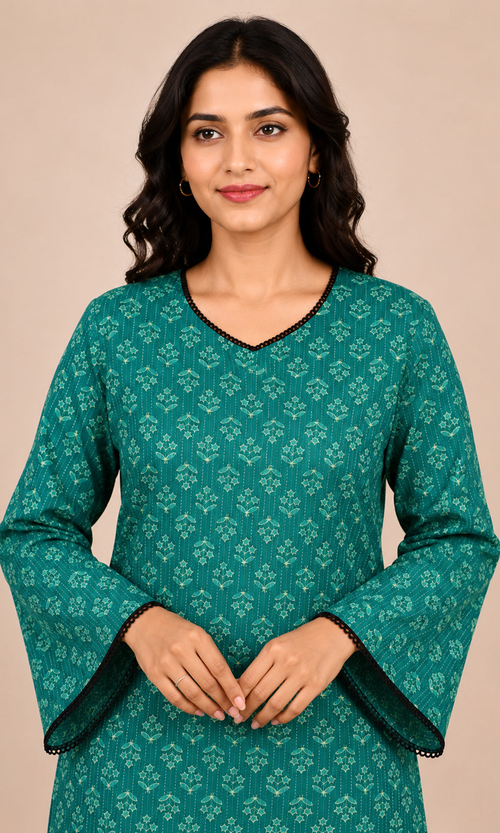 A woman wearing a teal green long-sleeve kurta with a light green floral block print and black scalloped trim, posed against a solid beige background.