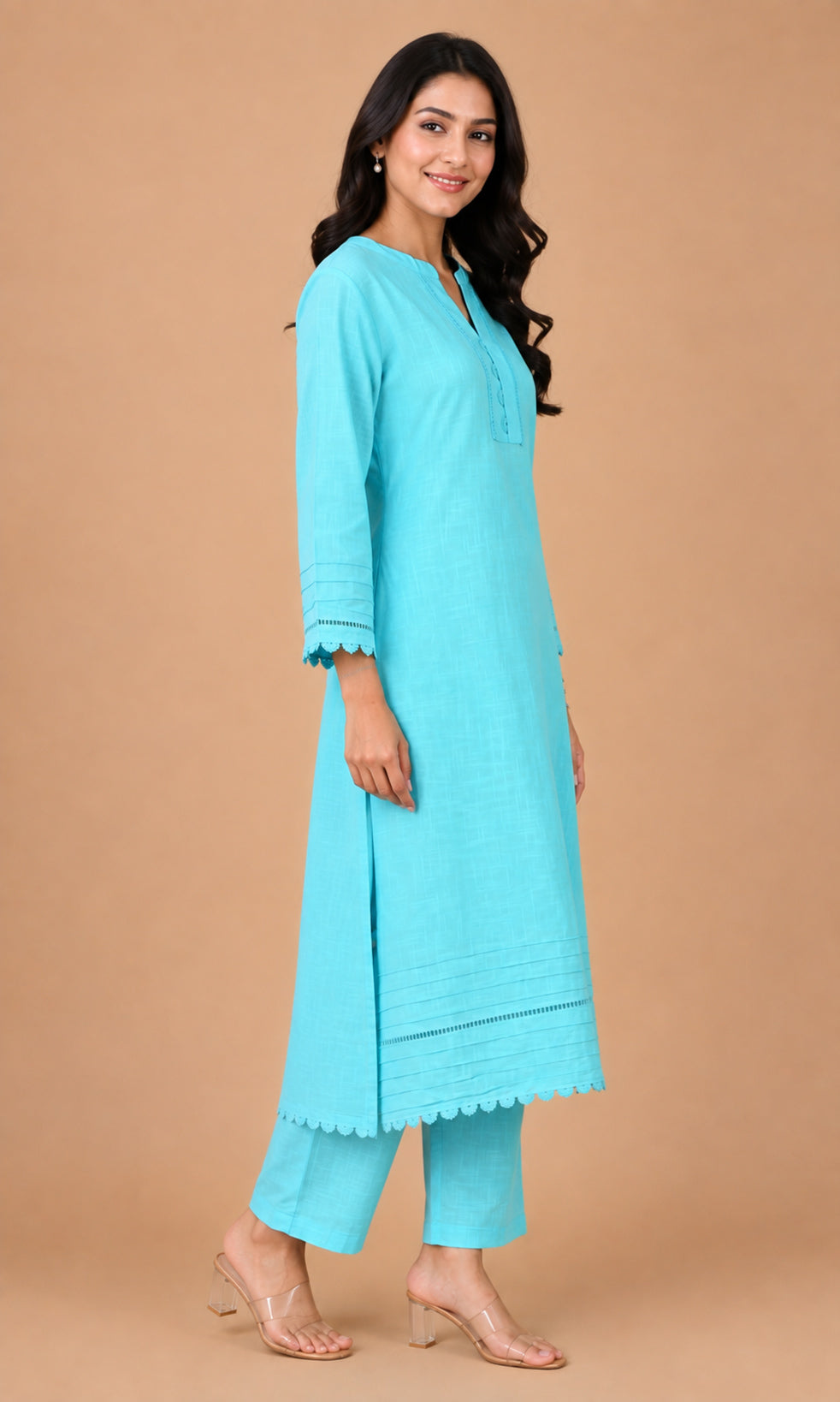 A woman modeling a light turquoise blue kurta and matching trouser set against a solid beige studio background.